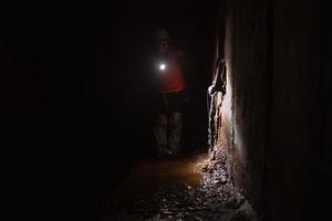 femmina scavatrice con torcia elettrica esplora il tunnel foto