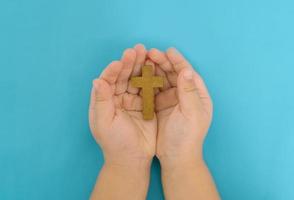 mani di un bambino con una croce cristiana in legno foto