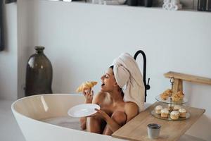 lusso moda donna nel il mattina prendere prima colazione dire bugie nel bagno foto