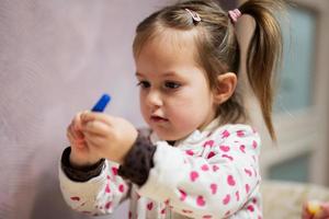 bambino ragazza con trecce decorazione arte con luccichio arredamento tubo di dipingere. foto