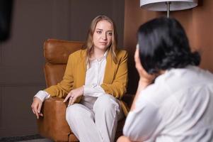 un' psicologo ragazza ascolta per un' cliente seduta nel un poltrona foto