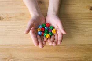 del bambino mani hold un' lotto di multicolore giocando dado foto