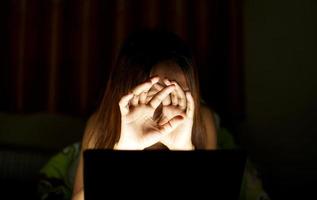 asiatico donne soffrire a partire dal affaticamento degli occhi a partire dal guardare a computer nel Basso luce. orologio film in linea foto