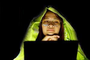 asiatico donna indossare bicchieri per Visualizza il computer nel Basso leggero orologio film in linea foto