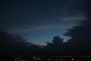 buio blu nube con bianca leggero sole impostato cielo sfondo e città leggero mezzanotte sera tempo foto