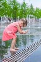 poco ragazza giocando su un' acqua Fontana foto