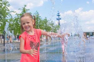 poco ragazza giocando su un' acqua Fontana foto