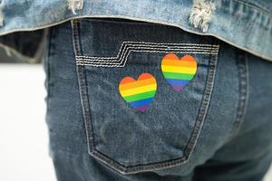 la signora asiatica con il cuore della bandiera arcobaleno, simbolo del mese dell'orgoglio lgbt, celebra l'annuale a giugno sociale di gay, lesbiche, bisessuali, transgender, diritti umani. foto