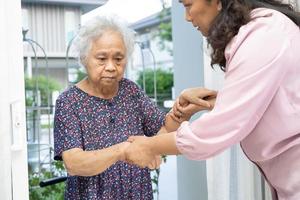 badante Aiuto e supporto asiatico anziano donna mentre a passeggio, passo su per il porta di il Casa. foto
