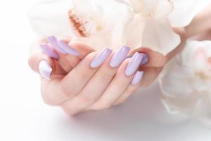 ragazze mani con delicato viola manicure e orchidea fiori foto