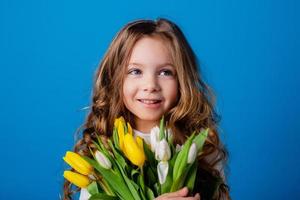 ritratto di un' affascinante sorridente poco ragazza con un' mazzo di tulipani nel sua mani. stile di vita. fresco fiori. internazionale Da donna giorno. spazio per testo. alto qualità foto