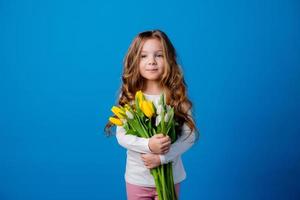 ritratto di un' affascinante sorridente poco ragazza con un' mazzo di tulipani nel sua mani. stile di vita. fresco fiori. internazionale Da donna giorno. spazio per testo. alto qualità foto