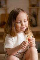 carino poco ragazza mangia naturale pastiglia a casa nel un' di legno cucina. cibo per bambini a partire dal naturale prodotti foto