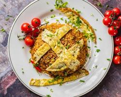 speziato indiano pollo biriyani frittata servito con coriandolo su un' bianca piatto e rosso pomodori su il lato. foto