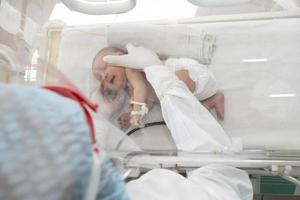 un' neonato bambino bugie nel scatole nel il Ospedale. un' bambino nel un incubatrice. neonatale e precoce intensivo cura unità foto
