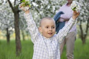 un' contento bambino nel un' fioritura primavera giardino gioisce, sorrisi. foto