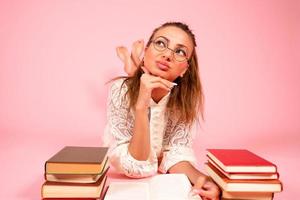 rosa sfondo, un' ragazza legge libri, un' libro amante, un' alunno bugie su il pavimento tra un' grande numero di libri foto