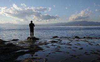 spettacolare scenario a il costa di enoshima, Giappone, con un' solitario pescatore in piedi a il bordo per il acqua foto