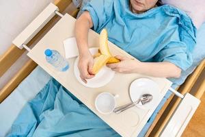 superiore Visualizza di donna peeling Banana nel ospedale letto foto