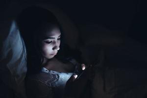 asiatico donna giocando gioco su smartphone nel il letto a notte, Tailandia persone, tossicodipendenti sociale media foto