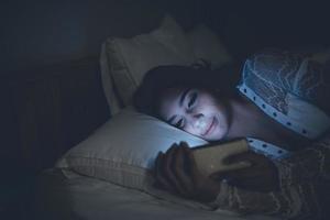 asiatico donna giocando gioco su smartphone nel il letto a notte, Tailandia persone, tossicodipendenti sociale media foto