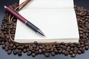 un' libro Aperto il vuoto pagina su il arrostito caffè fagioli con isolato nero sfondo. foto