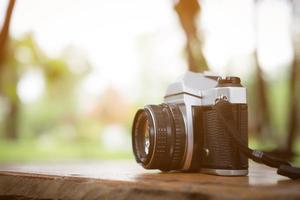 fotocamera vintage sul tavolo di legno con sfondo sfocato della natura foto