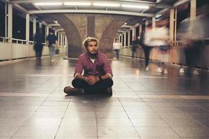 uomo barbuto hipster seduto sul pavimento mentre si viaggia di notte foto