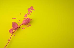 rivestimento rosa, gocciolante con inchiostro acrilico rosa bagnato, ammollo, piatto di colore fluido, isolato su sfondo astratto giallo colorato vivido foto