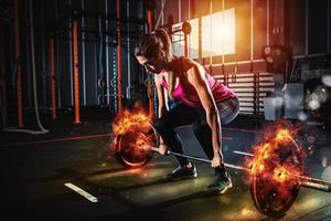 atletico ragazza lavori su a il Palestra con un' ardente manubrio foto