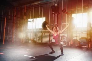 atletico ragazza lavori su a il Palestra con un' manubrio foto