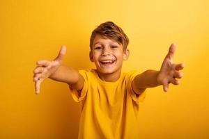 contento e gioioso bambino vuole per abbraccio qualcuno. giallo sfondo colore foto