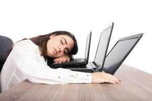 femmina lavoratore cascate addormentato mentre contemporaneamente Lavorando su tre computer portatili foto