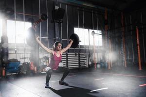 atletico ragazza lavori su a il Palestra con un' manubrio foto