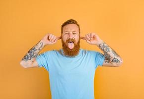 uomo con barba e tatuaggio bastoni il suo lingua su foto