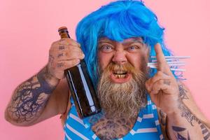 Grasso uomo con barba e parrucca fuma sigarette e bevande birra foto