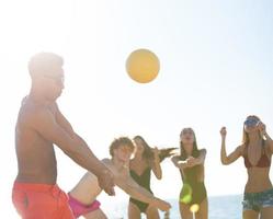 gruppo di amici giocando a spiaggia volley a il spiaggia foto