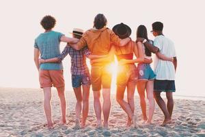 gruppo di contento amici avendo divertimento a oceano spiaggia foto