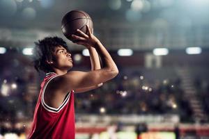 pallacanestro giocatore lanci il palla nel il cestino nel il stadio pieno di spettatori foto