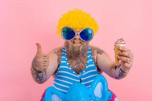 Grasso uomo con barba e parrucca mangia un gelato foto