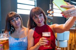 Due femmina amici prendere un' autoscatto mentre potabile birra foto