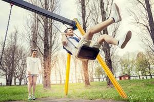 giovane donna spinge sua fidanzato su il swing foto