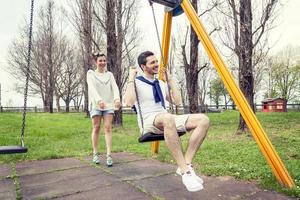 giovane donna spinge sua fidanzato su il swing foto