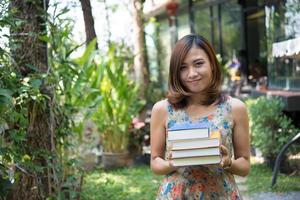 felice giovane donna in piedi e tenendo i notebook nel giardino di casa foto