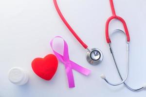 nastro rosa, stetoscopio e cuore rosso su sfondo bianco foto