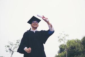 felice studente laureato in possesso di un diploma in mano foto