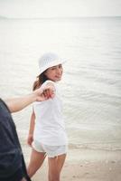 la ragazza porta il suo ragazzo in spiaggia foto