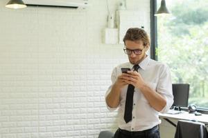 giovane imprenditore utilizza lo smartphone mentre si lavora in ufficio