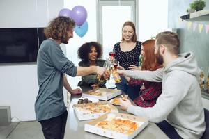 giovane amici mangiare Pizza e bevanda birra avendo divertimento insieme a casa. foto