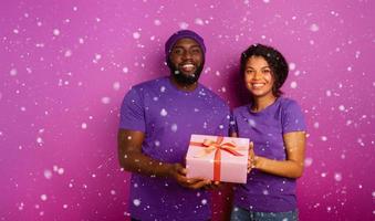 contento e gioioso coppia mostrare loro Natale regalo. viola sfondo foto